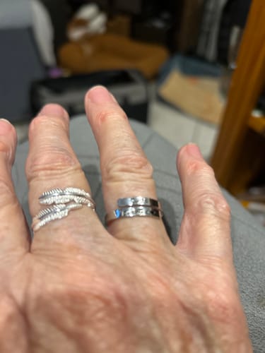 Close-up of a reviewer's hand wearing the silver, wrap-style Just Breathe Ring.