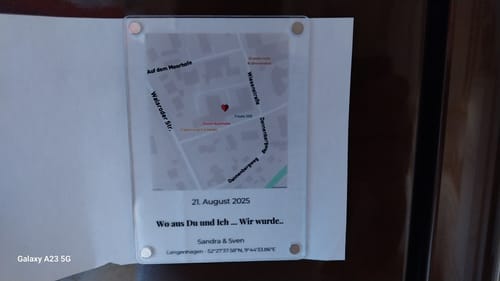 Ein Kunde zeigt den personalisierten Acryl-Magneten „Unser Ereignis“ mit einer Karte und einem Datum in einer aufklappbaren Karte.