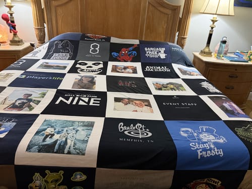 Customer's finished Premium T Shirt Quilt with many t-shirt and photo squares on a bed.