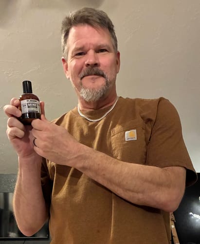 Recensore che tiene in mano una piccola boccetta di profumo ST INCENSE.