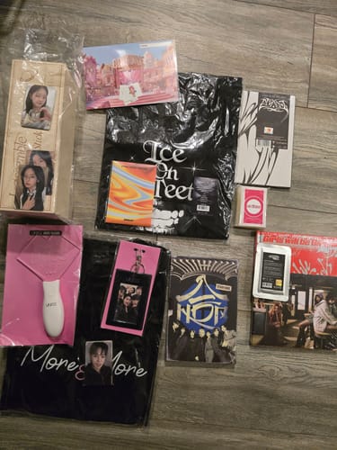 Customer's unboxed K-POP RANDOM BOX contents, including albums, t-shirts, and a lightstick, spread out on a floor.