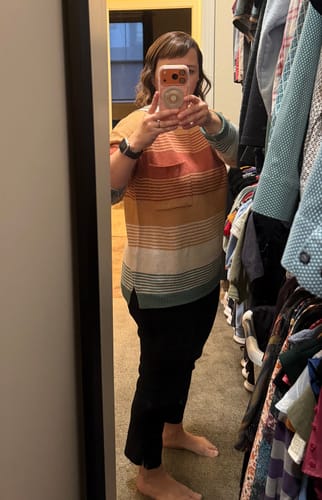 Reviewer in a closet wearing the striped Horizon Pocket Accented Sweater with black pants.