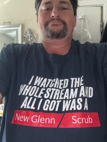 Reviewer wearing the dark navy New Glenn Scrub t-shirt, showing the text graphic on the front.
