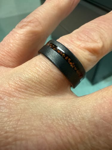 Close-up of a reviewer's finger wearing the black T-Rex ring with its red bone inlay.
