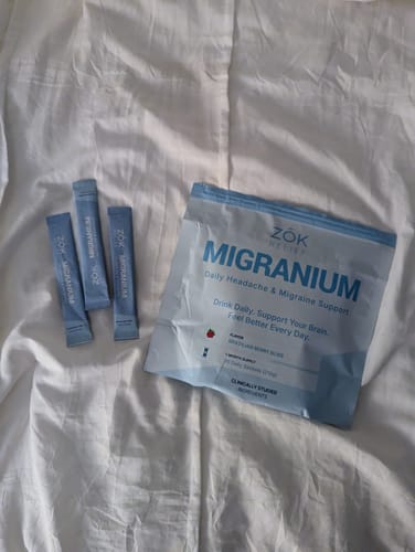 Customer's Migranium pouch and three single-serving sticks arranged on a white fabric surface.