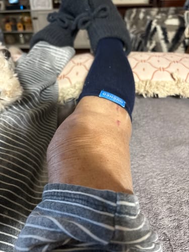Close-up of a customer wearing a navy blue Performance Eucalyptus Compression Sock while resting.