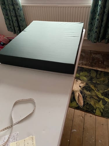 Reviewer's finished dog bed made from dark green waxed cotton fabric, shown on a white table.