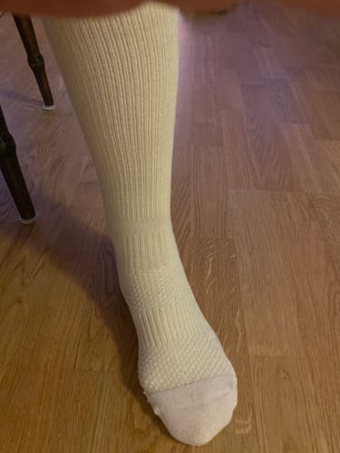 En kund visar en benvit Diasocks stödstrumpa på foten i en närbild.