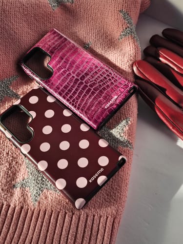 Customer's Couture Burgundy polka-dot case and a pink croc-pattern case styled on a pink sweater.