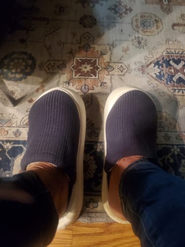 A top-down view of a customer's feet in dark, ribbed Flummys Slides with thick white soles.