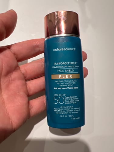 Reviewer holding the teal bottle of Colorescience Face Shield Flex SPF 50.