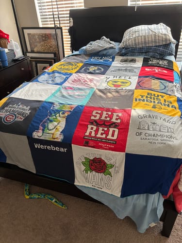 Customer's custom Premium T Shirt Quilt with various colorful shirt panels, spread across a bed.