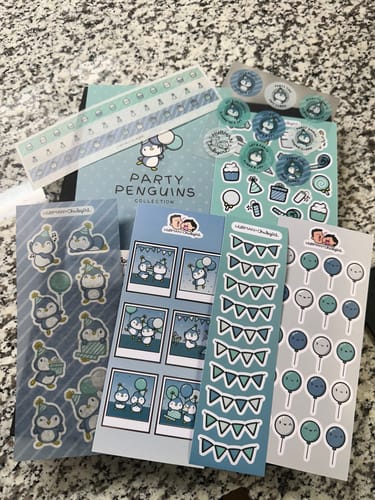 Customer's Sticker Subscription with the Party Penguins theme, showing various fun sticker sheets laid out on a counter.