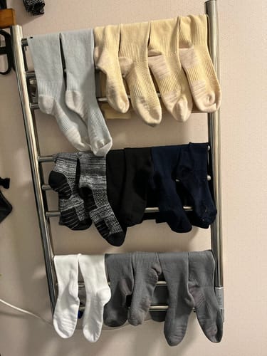 Kundens samling av Diasocks stödstrumpor i olika färger som hänger för att torka på ett element.