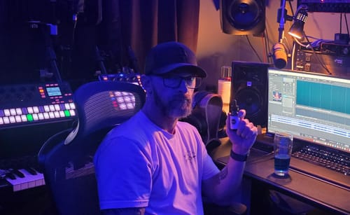 Reviewer in a studio holding a bottle of Meraki Blu Methylene Blue, with a glass of blue liquid on the desk.