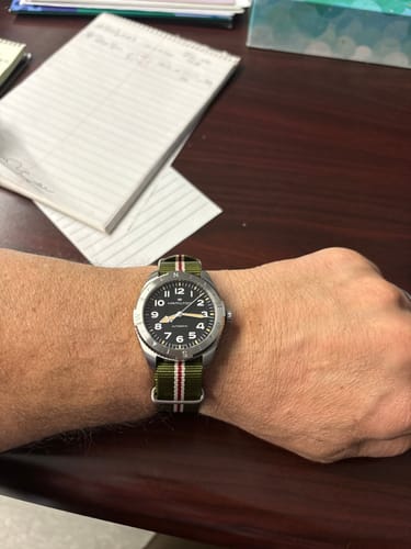 Customer showing the Original - English Holly strap on their wrist, paired with a silver field watch.