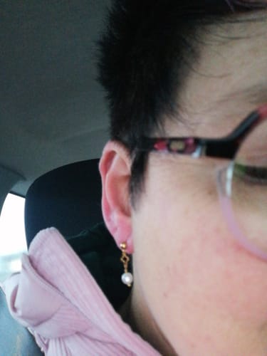 Nahaufnahme eines Rezensenten, der den goldenen Pearl Clover Ohrstecker mit baumelnder Perle im Ohr trägt.