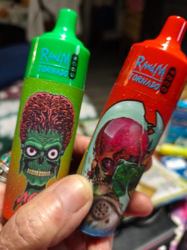 Customer holds two RandM 9000 Puffs disposable vapes with colorful alien graphics.