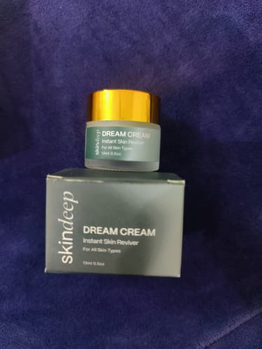 Reviewer's skindeep Dream Cream jar with a gold lid, sitting on its dark grey packaging box.