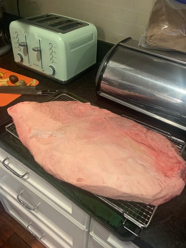 Customer's large, raw USDA Prime Brisket resting on a wire rack on a kitchen counter before being cooked.