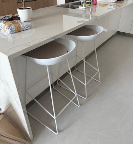Customer's two chic white bar stools tucked under a marble kitchen island.