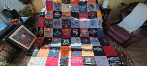 Customer's large Premium T Shirt Quilt, made from many different t-shirts, spread out on a sofa.