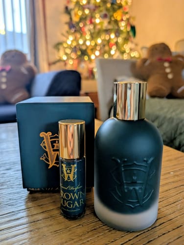 Customer's full-size and travel-size Brown Sugar perfume bottles on a wooden table with festive decor.