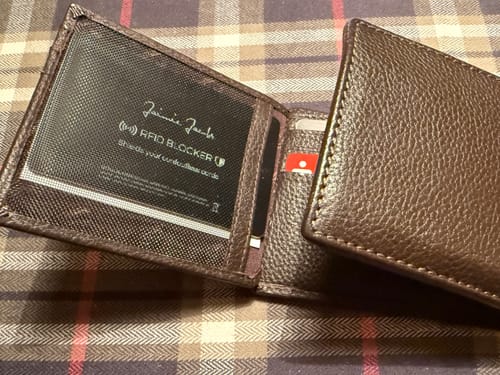 Customer's brown wallet open to show the RFID protection card in a mesh pocket on a plaid surface.