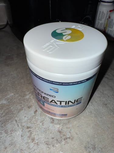 Un client montre le pot de Créatine Micronisée de Believe sur un comptoir.