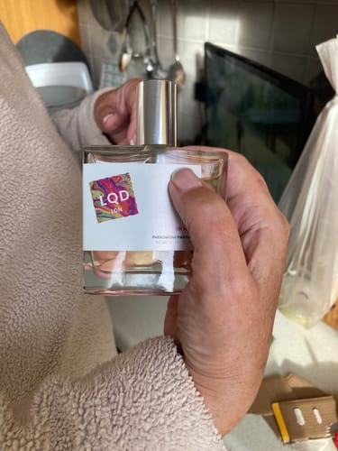 Customer holding the rectangular bottle of For Her Pheromone Perfume with a shiny silver cap.