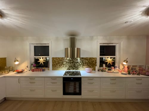 Et frontbilde fra en kunde som viser hexagon gullfliser installert symmetrisk som backsplash.