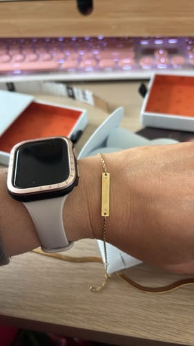 Customer wearing the delicate gold Engravable Bracelet With Stones on their wrist next to a watch.