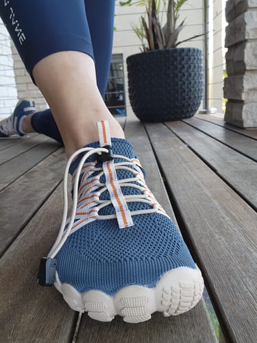 Close-up of a customer wearing the blue Breeze IV Barefoot Shoes, highlighting the mesh fabric and flexible white sole.