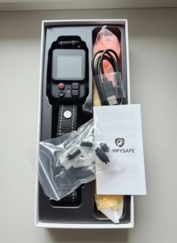 Photo d'un client montrant le collier anti-fugue GPS et ses accessoires dans la boîte ouverte.