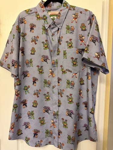 Reviewer's Teenage Mutant Ninja Turtles "Out of Their Gourds" short-sleeve shirt hanging on a hanger, showing the all-over character print.