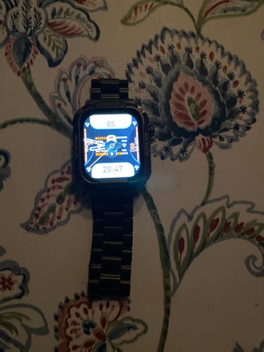 Recensent toont het zwarte stalen bandje gemonteerd op een smartwatch die op een tafel ligt.