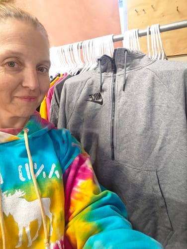 Reviewer showing a grey branded sweatshirt from their wholesale order, hanging on a rack with other sweatshirts.