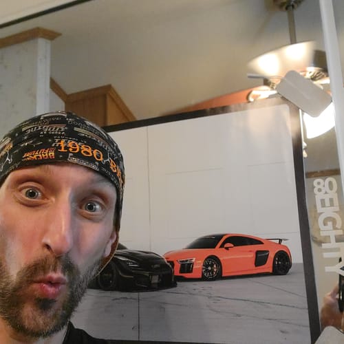 Reviewer holding up the 80Eighty® Limited Edition DCG 83/84 Poster showing two sports cars.