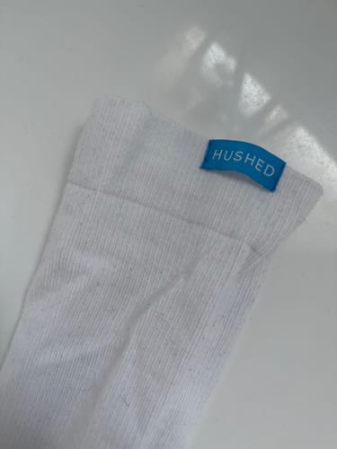 Close-up of a customer's white Performance Eucalyptus Compression Sock, showing the blue brand tag at the cuff.