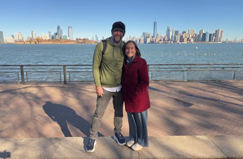 Reviewer showing the fit of their Surplus Olive – Performance Hoodie while standing outdoors by the water.