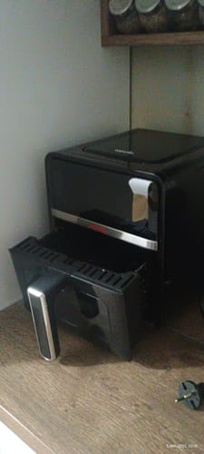 Client prezentând friteuza Novio StonePro pe blatul din bucătărie, cu cuva scoasă.