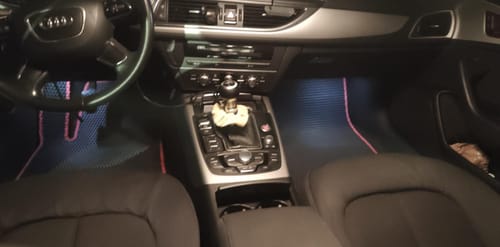 Recenzent pokazuje czarne dywaniki samochodowe z różowym obszyciem zainstalowane w przedniej części samochodu.