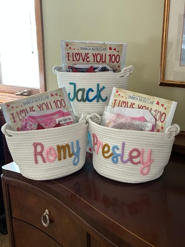 Customer's three white personalized knitted baskets with the names Jack, Romy, and Presley, filled with gifts.