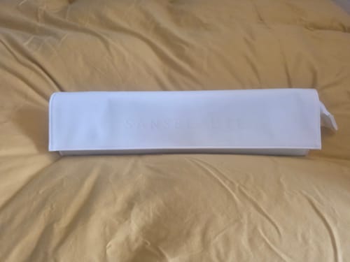 Recensent toont het stijlvolle, witte SANSBEAUTÉ reisetui op een bed.
