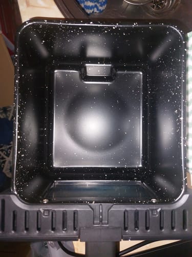 Clientul arată cuva friteuzei Air Fryer Novio StonePro, evidențiind interiorul negru cu acoperire din piatră Maifan.