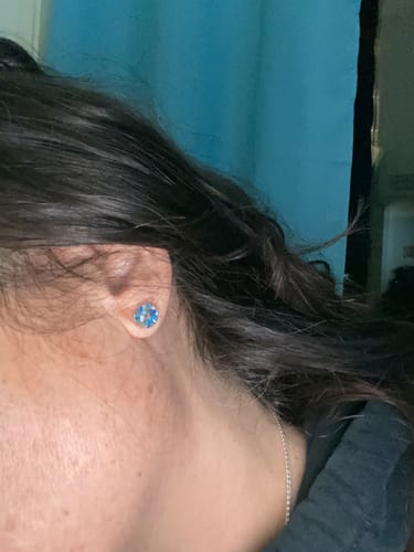 Close-up of a reviewer wearing a sparkling blue Opal Stud Earring.