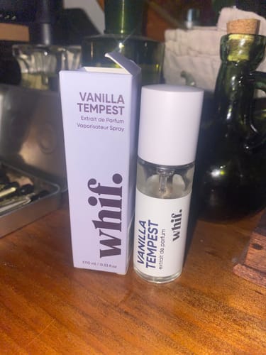 Customer's Vanilla Tempest perfume bottle next to its light purple box on a wooden table.