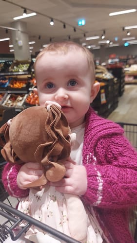 A customer's child holding their Personalized Princess Breeze doll while sitting in a shopping cart.