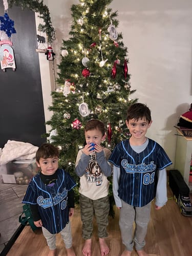 Customer shows two children wearing the navy and light blue pinstripe baseball jersey in front of a Christmas tree.