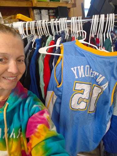 Customer smiling next to a clothing rack filled with items from their Wholesale Kids Mix.
